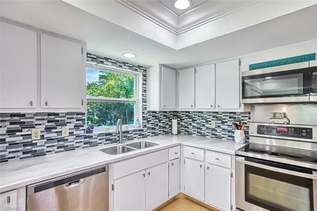 a kitchen with stainless steel appliances white cabinets a sink and a stove