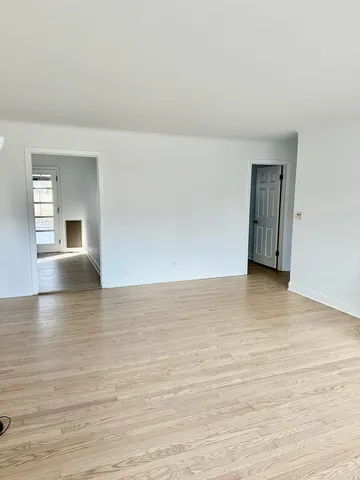 a view of an empty room with wooden floor and closet
