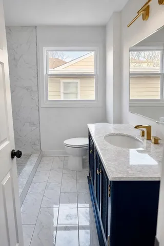 a bathroom with a granite countertop sink a toilet and a mirror