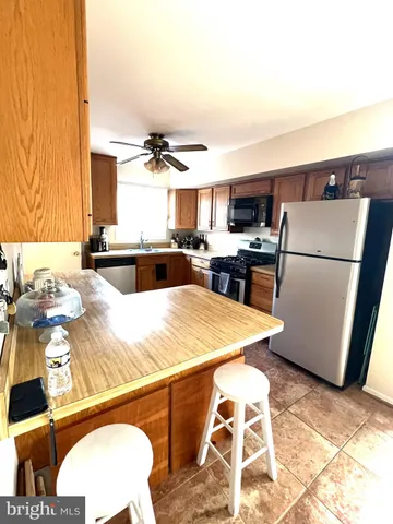 a kitchen with stainless steel appliances granite countertop a refrigerator a stove a sink dishwasher and a dining table with wooden floor