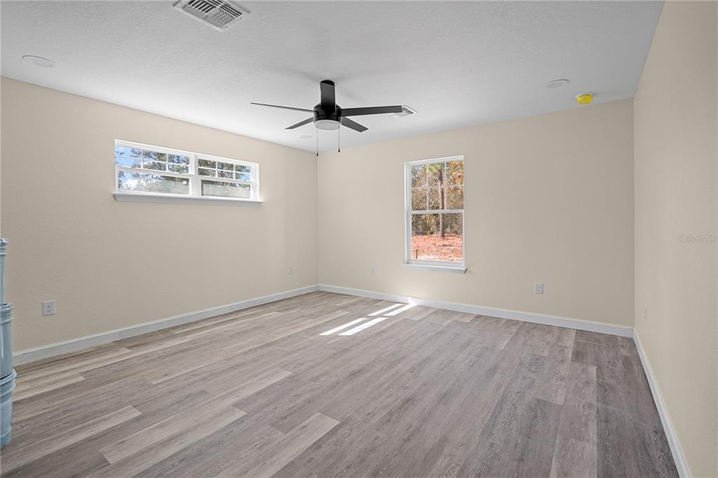 2988 Southwest Bonable Drive Dunnellon, FL 34431 - Photo 13 of 19 an empty room with wooden floor ceiling fan and windows