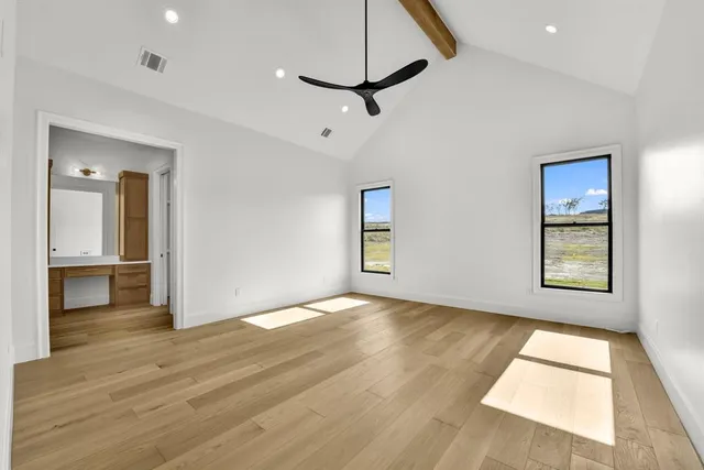 a view of empty room with wooden floor and fan