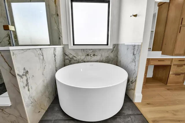 a white bath tub sitting next to a white sink and a mirror