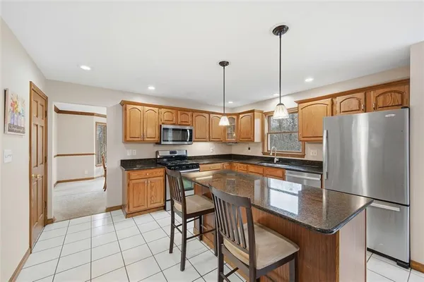 a kitchen with stainless steel appliances granite countertop a refrigerator a stove a sink a dining table and chairs with wooden floor