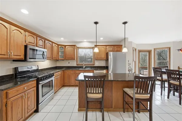 a kitchen with stainless steel appliances granite countertop a stove top oven a sink dishwasher and a wooden cabinets