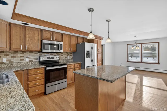 a kitchen with stainless steel appliances granite countertop a sink a stove and a wooden floors