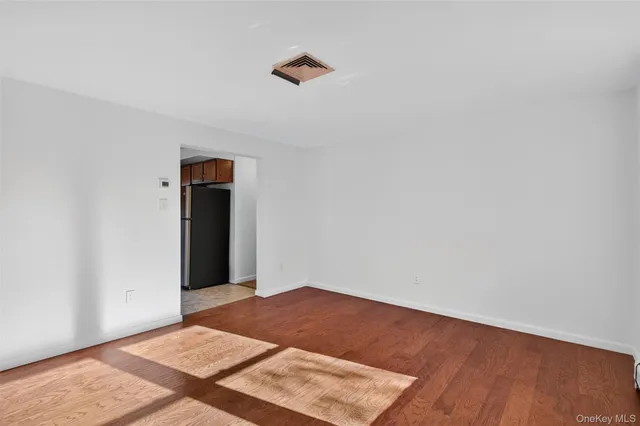 an empty room with wooden floor and fan