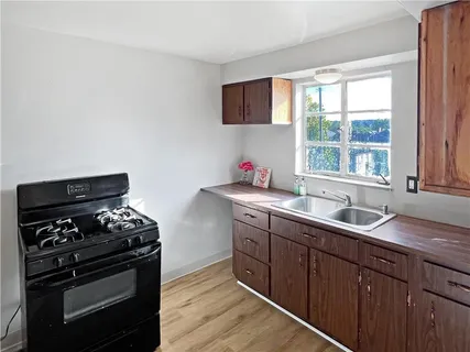 a kitchen with sink a stove and wooden floor