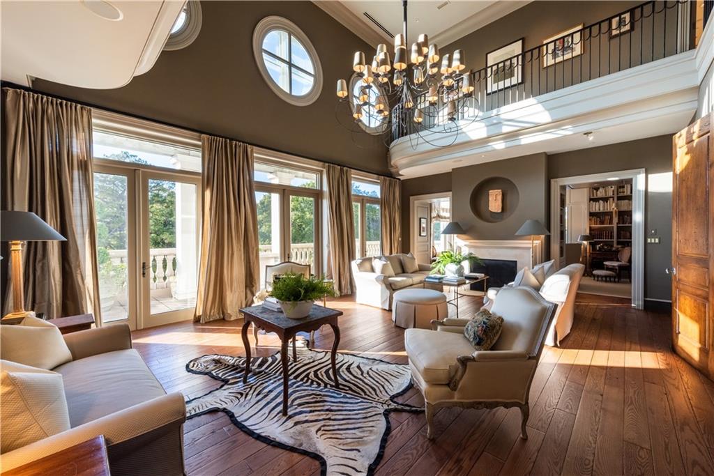 a living room with furniture a chandelier a large window and wooden floor