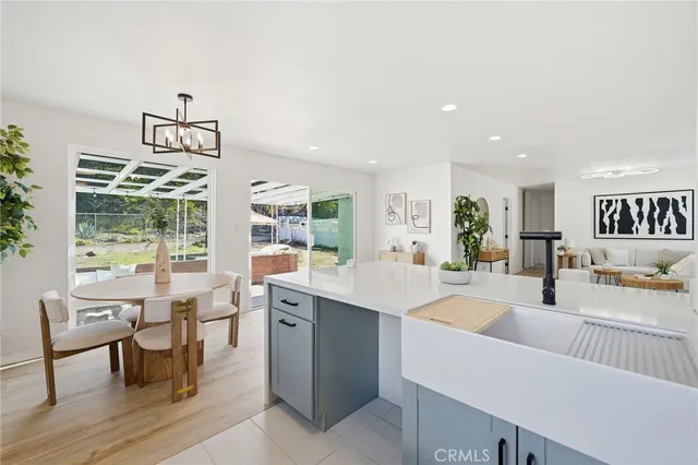 a room with stainless steel appliances kitchen island granite countertop a table chairs and a view of living room