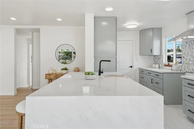 a large white kitchen with a sink and a large window