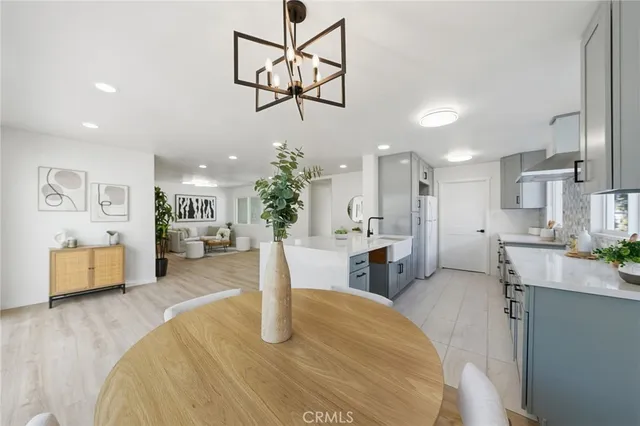 a dining room with wooden floor a chandelier a glass table and chairs