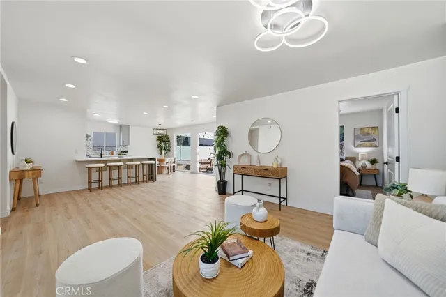 a living room with furniture kitchen view and a chandelier