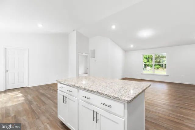 an entryway with granite countertop white cabinets and wooden floor