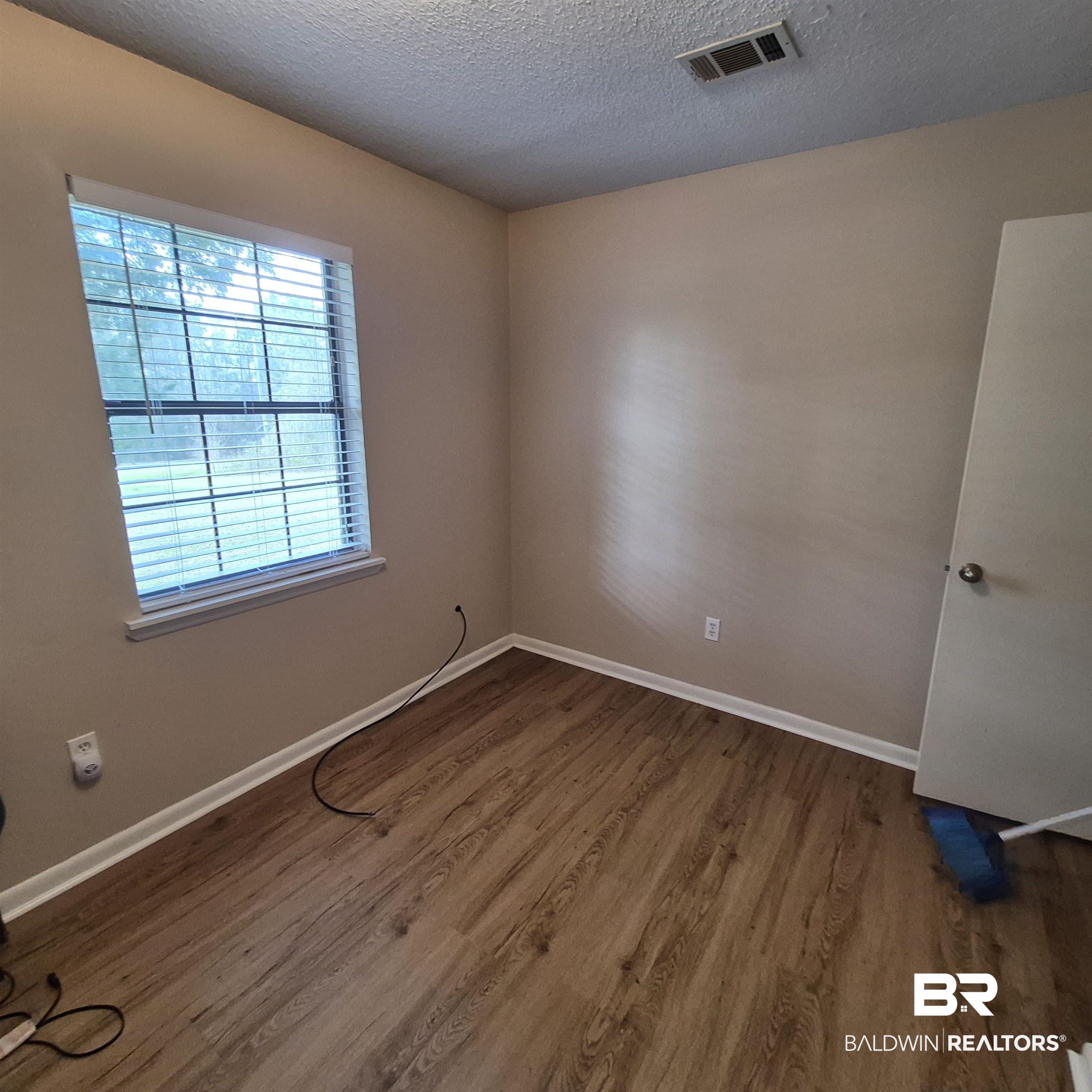 721 Perryman Street Evergreen, AL 36401 - Photo 15 of 26 Empty room with wood finished floors and a textured ceiling