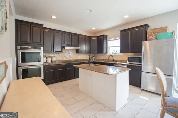 a kitchen with kitchen island a refrigerator sink and cabinets