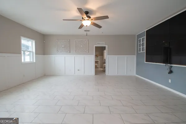 an empty room with windows and ceiling fan