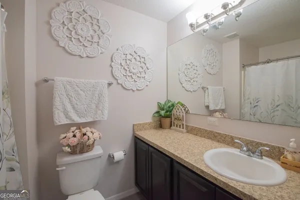a bathroom with a granite countertop sink a toilet and a mirror
