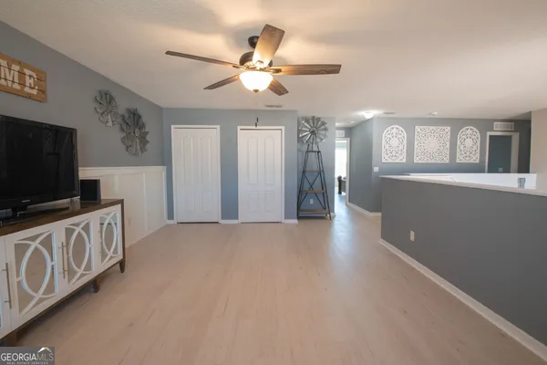 a view of a livingroom with furniture a flat screen tv wooden floor and chandelier
