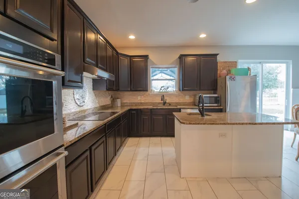 a kitchen with stainless steel appliances granite countertop a refrigerator a stove and a sink