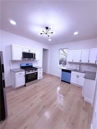 a large kitchen with kitchen island granite countertop a stove top oven a sink and dishwasher with wooden floor