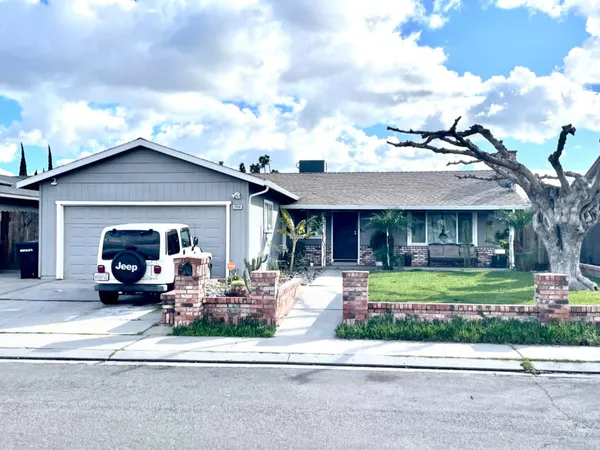 a front view of a house with a garden and trees