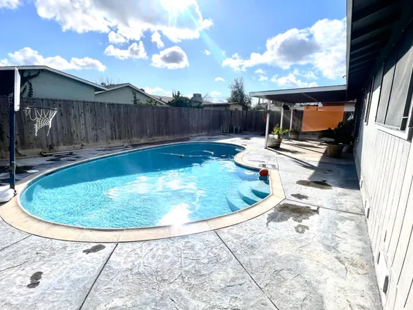 a view of a backyard with swimming pool and sitting area