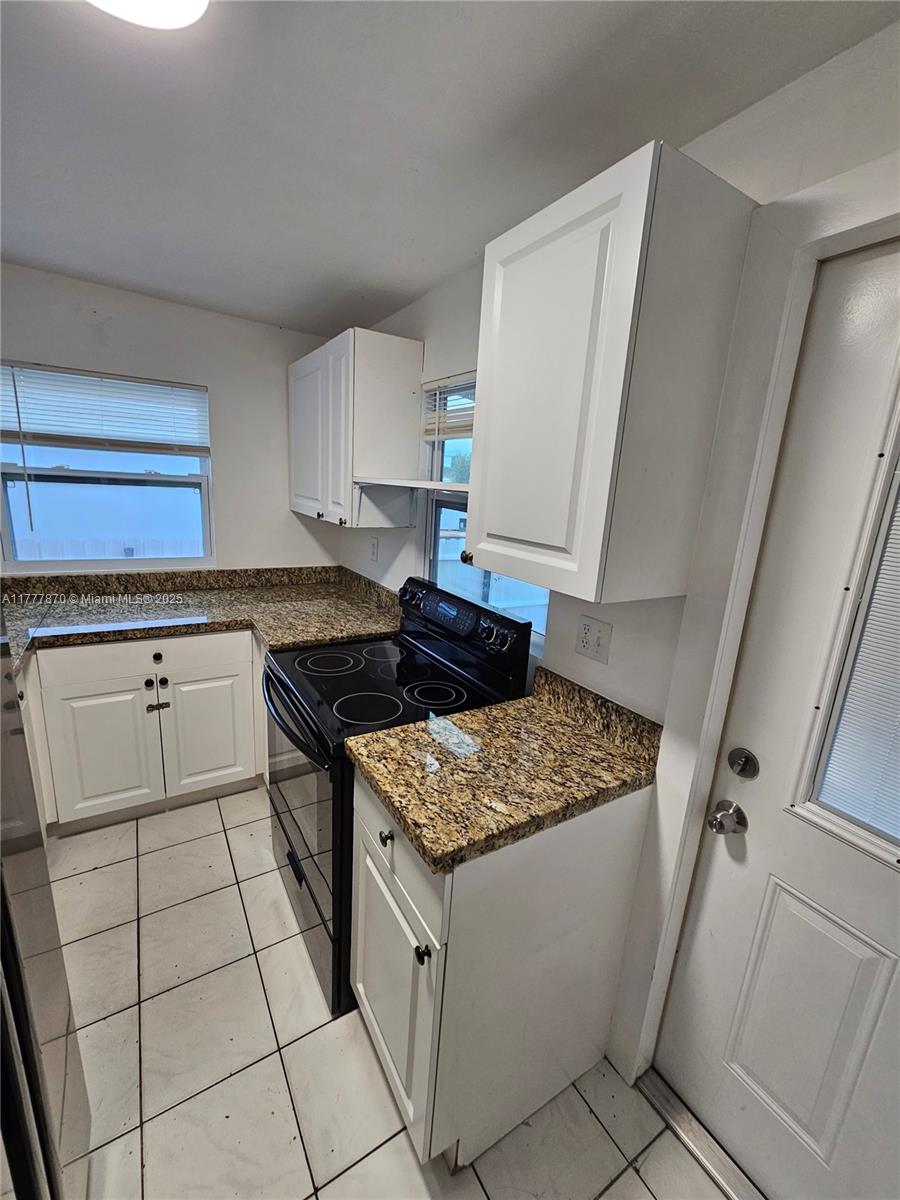 330 Southwest 79th Court, Unit 2 Miami, FL 33144 - Photo 5 of 9 a kitchen with a stove top oven and cabinets