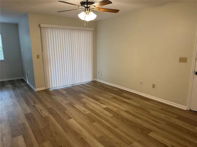 an empty room with wooden floor fan and windows
