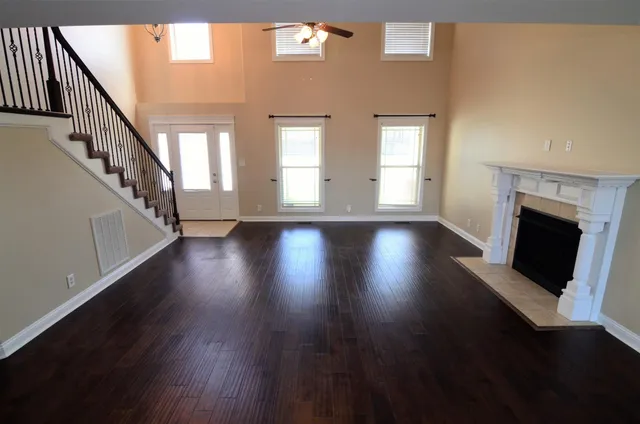 a view of an empty room with wooden floor fireplace and a window