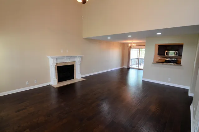 a view of an empty room with wooden floor and a fireplace