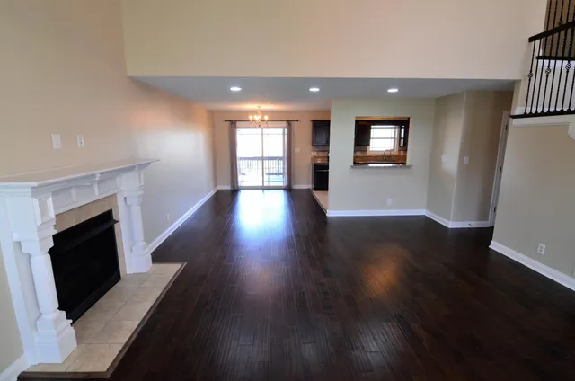 an empty room with wooden floor fireplace and windows