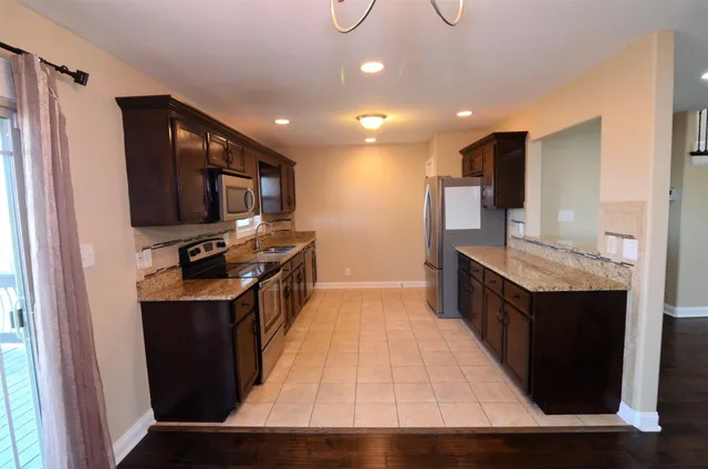 a kitchen with kitchen island wooden cabinets a sink a counter top space stainless steel appliances and a window