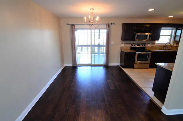 an open kitchen with wooden floor and stainless steel appliances