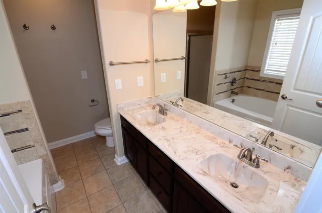 a bathroom with a granite countertop sink a mirror and a bathtub