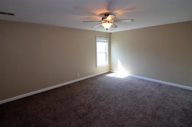 an empty room with windows and chandelier fan