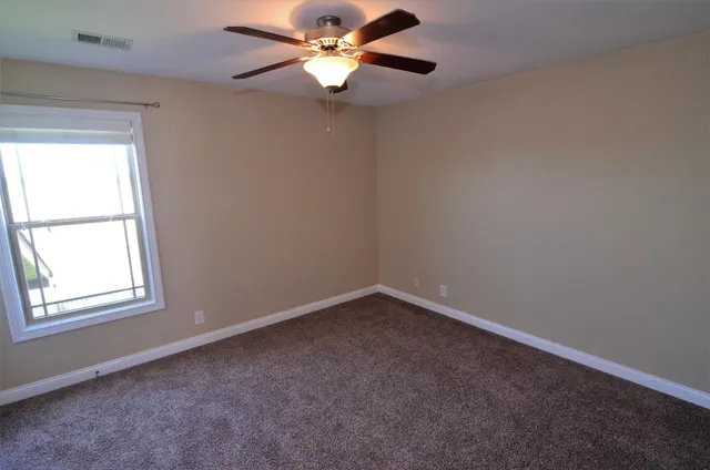 an empty room with a window and a fan