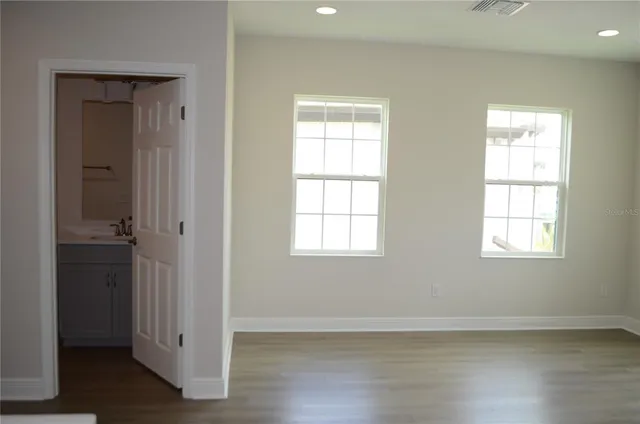 an empty room with wooden floor closet and windows