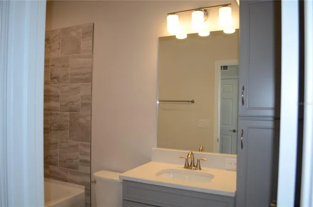 a bathroom with a granite countertop sink a mirror and a shower