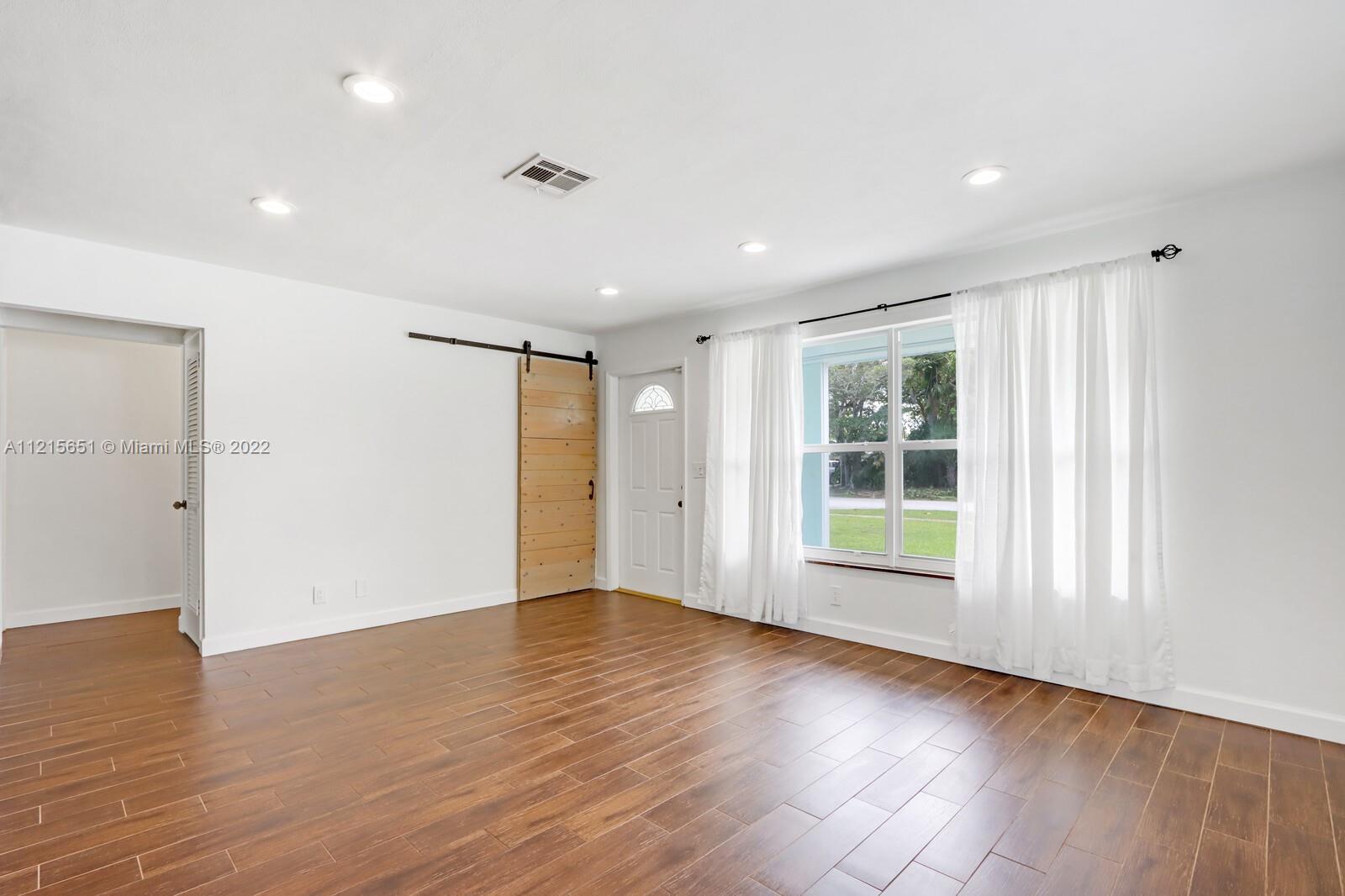 1515 Seabrook Road Jupiter, FL 33469 - Photo 6 of 29 a view of an empty room with wooden floor and windows