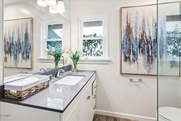 a bathroom with a granite countertop sink a toilet and shower