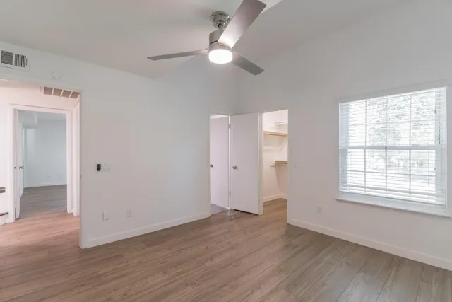 an empty room with wooden floor and windows