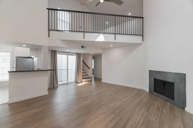 a view of an empty room with wooden floor and a kitchen