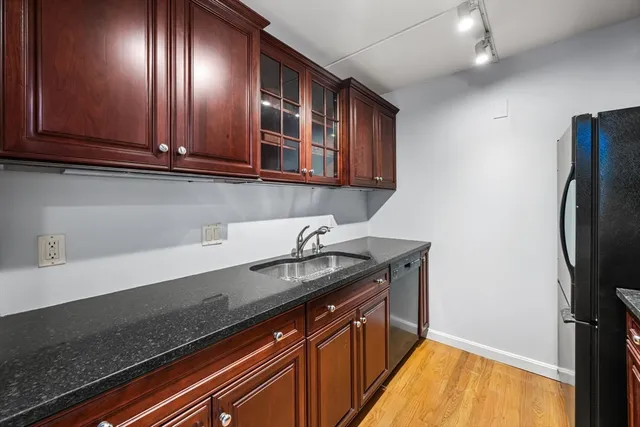 a kitchen with granite countertop stainless steel appliances a sink stove top oven and cabinets