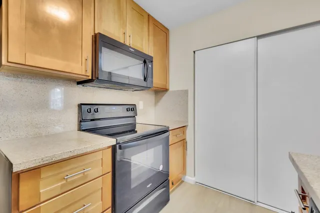 a kitchen with stainless steel appliances granite countertop white cabinets and a stove top oven