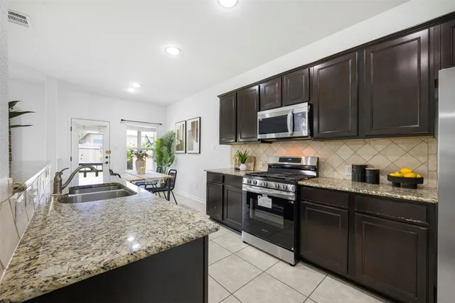a kitchen with stainless steel appliances granite countertop a sink stove and microwave
