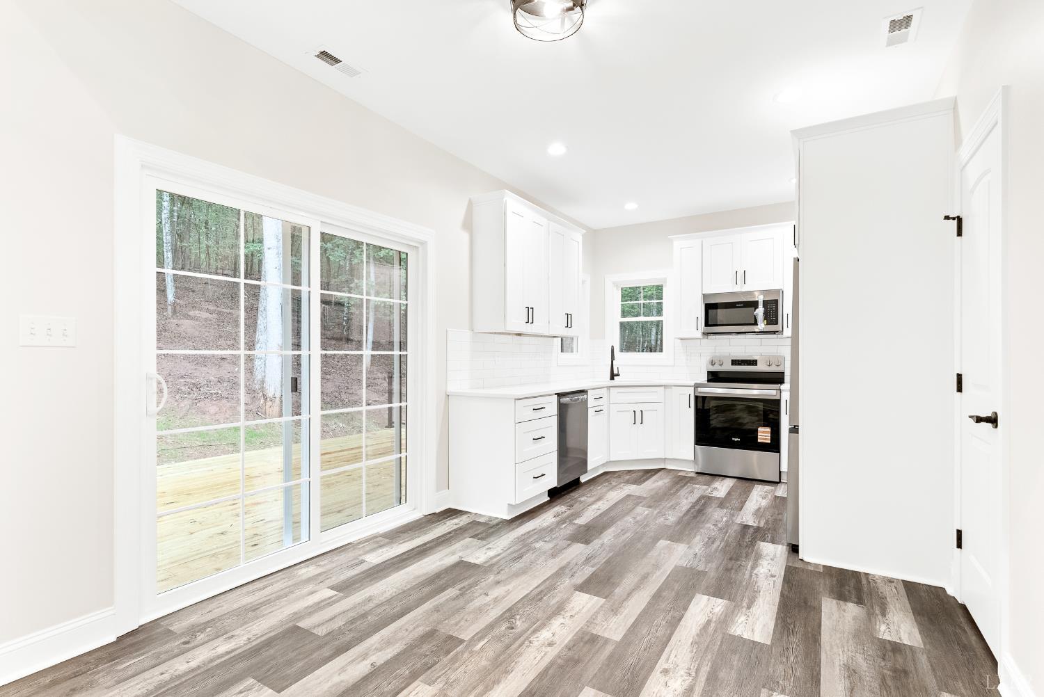 5610 Old Cifax Road Goode, VA 24556 - Photo 11 of 49 a kitchen with white cabinets and wooden floor