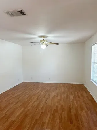 a view of an empty room with chandelier fan and a window