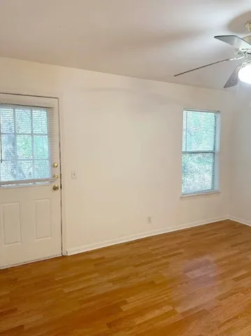 an empty room with wooden floor and windows