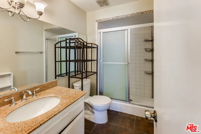 a bathroom with a granite countertop sink toilet a mirror and shower